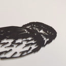 A close-up of Metalbird Australia's Tawny Frogmouth, a premium black metal silhouette, lies flat on a plain white surface, showcasing intricate cutout details for the eyes, beak, and feathers.