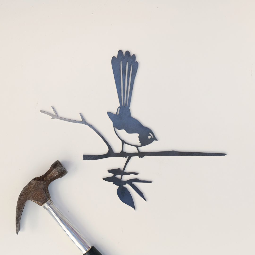 Willie Wagtail steel silhouette beside a wooden-handled hammer on a pale background.