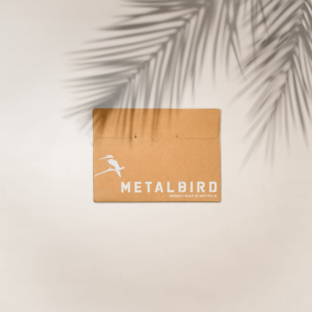 Brown Metalbird gift packaging with palm-leaf shadows.