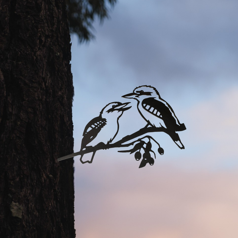 The "Pair of Kookaburras" by Metalbird Australia features a Corten steel silhouette depicting two native Laughing Kookaburras perched on a branch, designed to be easily attached to a tree trunk. With its striking form set against natural backdrops, this piece makes an ideal addition to Australian garden decor, bringing the unique charm of native wildlife into your outdoor space.