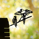 Two illustrated lorikeets perch on a branch, one with wings spread, against a vibrant green-yellow background. A dark silhouette of the Metalbird Australia "Pair of Lorikeets" premium corten steel yard art appears on the left.